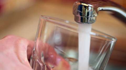 Pouring a glass with drinking water from kitchen tap