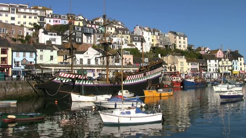 Brixham, Devon, UK - September 10 2009: Houses on the steep slopes rise above the boats in the port of Brixham in Devon England. A replica of Drake's ship the Golden Hind in moored at the quay.