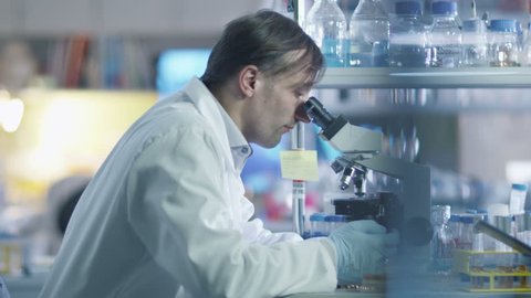 Two scientists are using a microscope and a tablet while working in a laboratory. Shot on RED Cinema Camera in 4K (UHD).