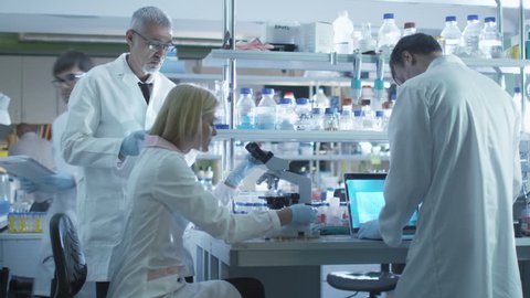Team of scientists in white coats are working with a laptop and tablet in a laboratory. Shot on RED Cinema Camera in 4K (UHD).