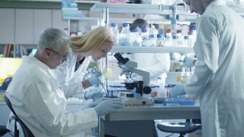 Group of caucasian scientists in white coats are working in a modern laboratory. Shot on RED Cinema Camera in 4K (UHD).