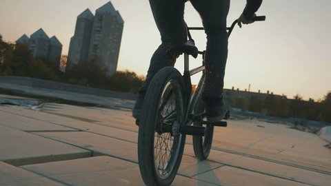 A bmx rider doing a trick in sunset in slow motion 