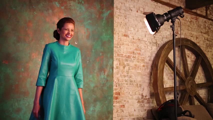Beautiful woman in green leather dress poses in studio