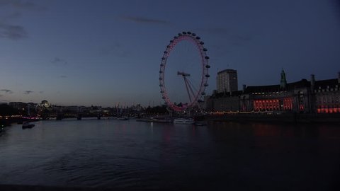 LONDON, ENGLAND - CIRCA 2015 - Boats pass the London Eye along the River Thames, England at night.