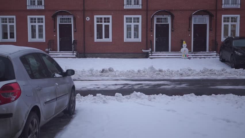 Snowing in front of red brick townhouses