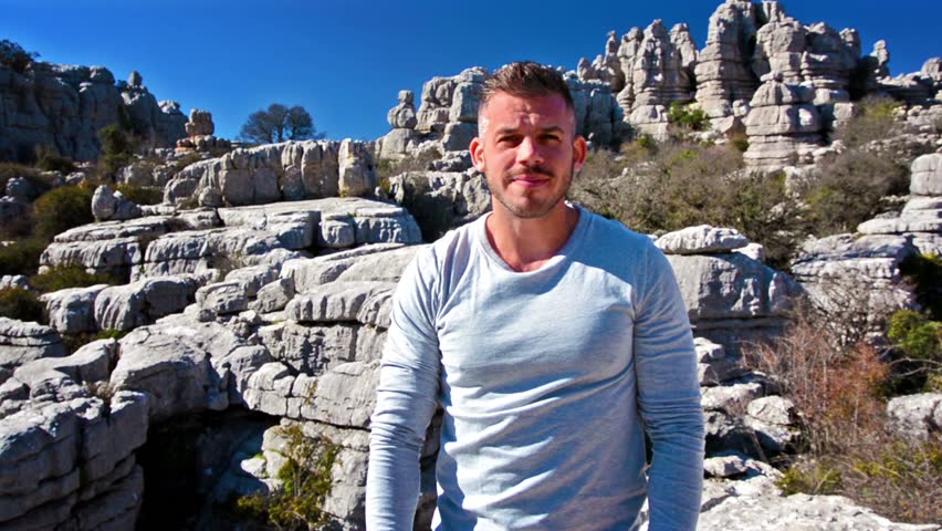 Young confident handsome man posing and smiling in nature on a sunny day. Torcal Antequera, Malaga, Spain