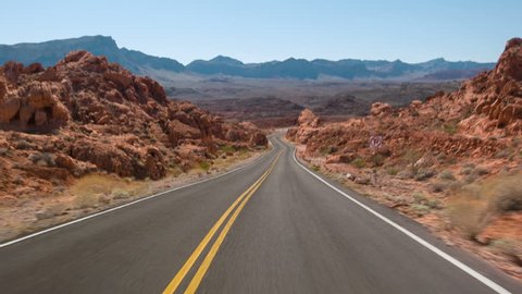 Driving USA: spectacular red rocks and mountains car point of view on lonely empty highway road in Valley of Fire, Nevada desert