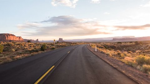 Driving USA: Sunset sunrise point of view shot along empty desert highway through Monument Valley, Arizona Utah