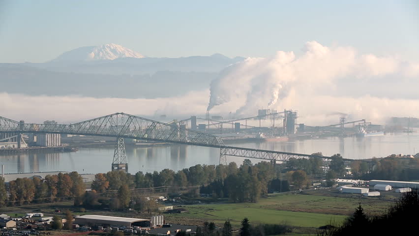 Longview, Washington Industry. Longview, Washington State, USA. The Lewis and Clark Bridge crossing the Columbia River between Washington and Oregon. The top of Mount St. Helens in the background. 

