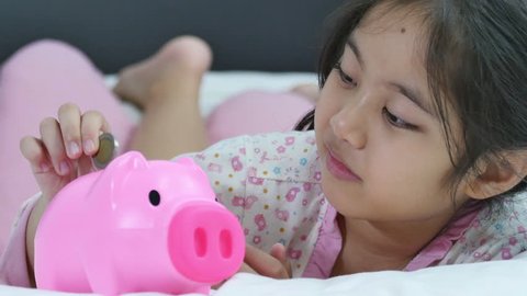 Happy Asian girl saving money in piggy bank