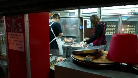 TAIPEI, TAIWAN - FEBRUARY 12, 2015: Unidentified man and woman make oriental dumplings manually, hand wrap minced meat filling into a thick circle of dough. Traditional Asian dishes preparation