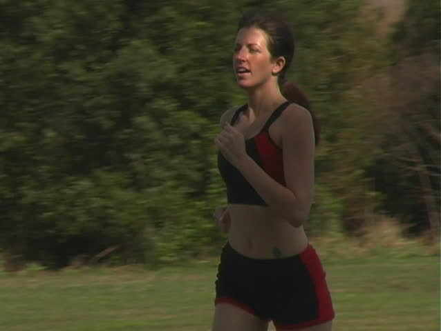 A beautiful young woman jogging outdoors.  Camera pans left to follow.