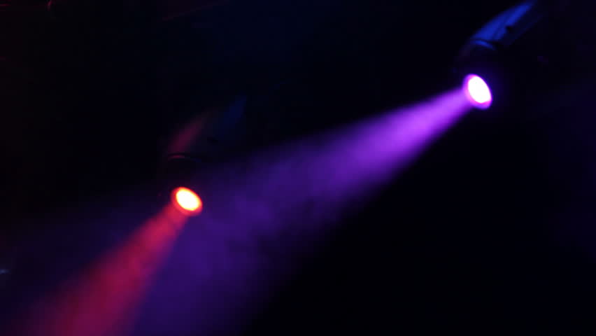 Professional stage lights on a dark stage. Red and purple lights move around and