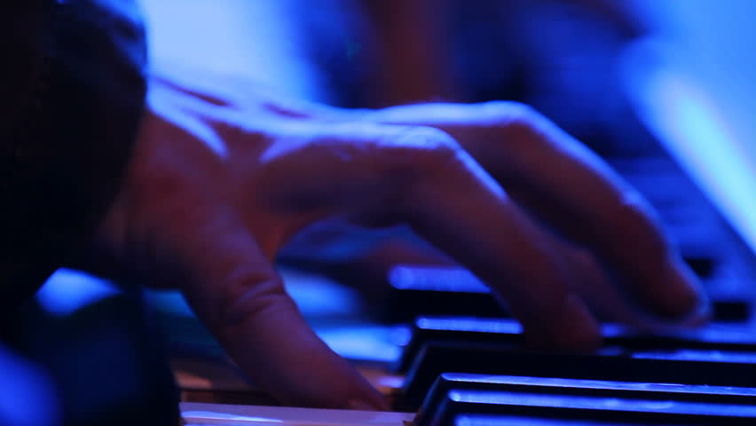 Close up of hands playing a keyboard in a creepy lighting setup.  Looks like