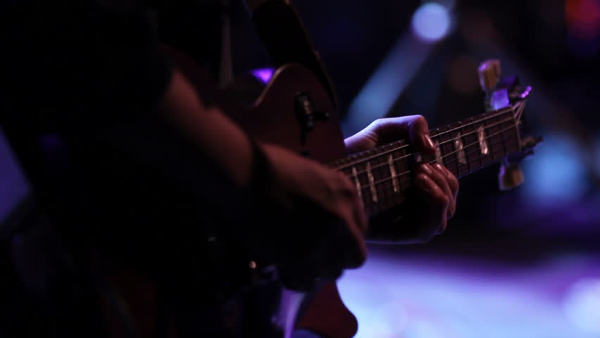This is a close up shot of a man playing lead guitar at a staged rock concert