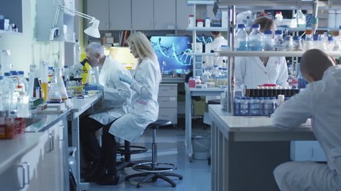 Team of caucasian scientists in white coats are working in a modern laboratory. Shot on RED Cinema Camera in 4K (UHD).