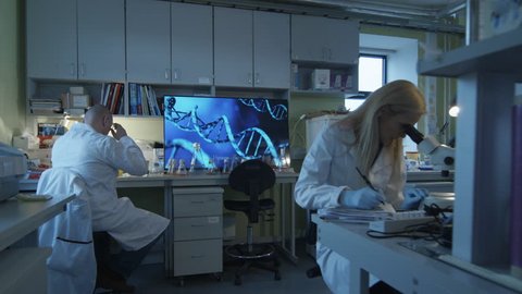 Group of caucasian scientists in white coats are working in a modern laboratory. Shot on RED Cinema Camera in 4K (UHD).