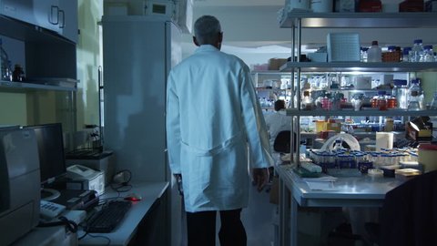 Senior scientist in white coat is greeting colleagues in a laboratory. Shot on RED Cinema Camera in 4K (UHD).