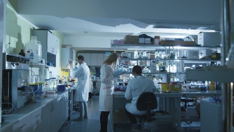 Team of caucasian scientists in white coats are working in a modern laboratory. Shot on RED Cinema Camera in 4K (UHD).
