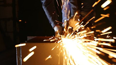 Worker working of a grinding machine with a lot of sparks