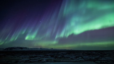Strong bright Aurora Borealis snow covered lava field mountains Thingvellir Iceland realistic movement 4k