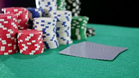 A gambler at a poker table peeks at his cards and bets a stack of chips