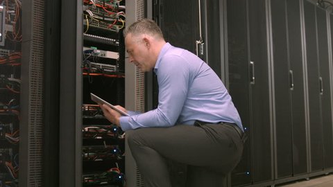 Technician using tablet pc while analysing server in high quality format