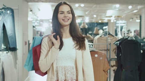 Happy young brunette girl is walking though a clothing store. Shot on RED Cinema Camera in 4K (UHD).