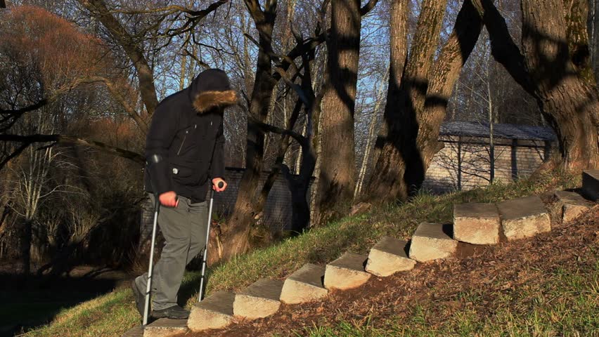 Disabled man on crutches walking up the stairs
