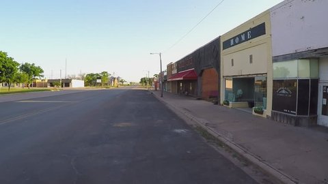 CROWELL, TX/USA - August 3, 2015: POV driving by storefronts in a farm town square. A driver passes by several small businesses in a small rural city along a vacant road in downtown area.