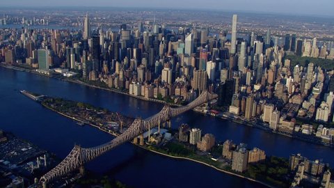 Aerial establishing shot of Midtown Manhattan over the East River, 59th Street Bridge and Roosevelt Island New York City on beautiful day. DX overhead point of view
