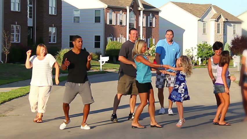 A happy group of neighborhood residents dance in the street.