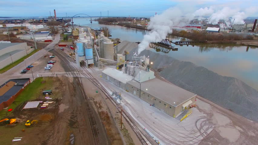 Beautiful factory smokestack smoke or steam with railroad bridge, aerial view.
