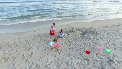 A drone shot slowly circles two young girls and their mom as they build a sandcastle on the Ocracoke Island beach. Aerial Shot 2015. Stock Video