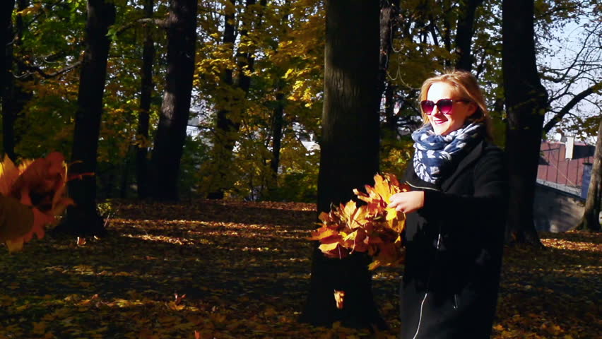 Couple throwing leaves in the park, slow motion shot
