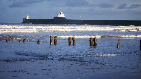 Surfers, strong waves and supply boat in the North Sea Beach, Aberdeen, Scotland
