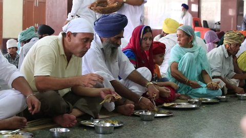 AMRITSAR, INDIA - SEPTEMBER 27, 2014: Unidentified poor indian people eating free food at a soup kitchen in the Golden Temple
