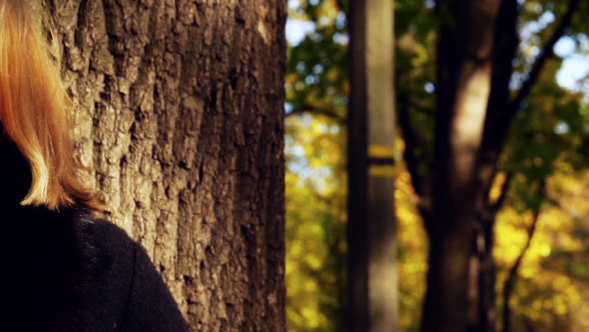 Beautiful woman leaning on tree in the park, slow motion shot at 240fps
