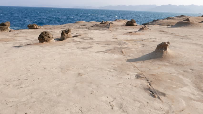 Small mushroom weathered stone at deserted Yehliu shore, parallax shot. Low evening sun light, flat smooth area, washed by waves and rains, hard cap on small odd stone formation
