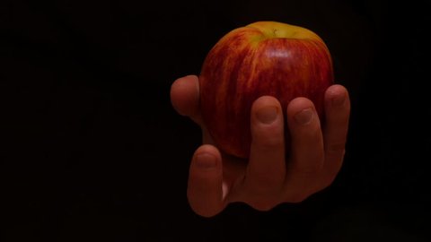 isolated hand with apple moves on black background 