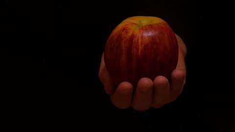 isolated hand with apple moves on black background 2