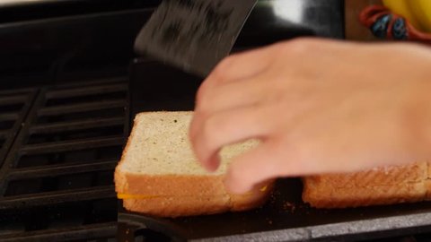 A dolly shot of a woman making gilled cheese sandwiches in the kitchen for lunch