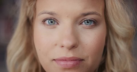 Dramatic Close up of beautiful blonde woman with bright blue eyes portrait happy smiling slow motion soft natural light on face center crop