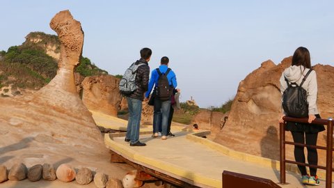 TAIPEI, TAIWAN - FEBRUARY 13, 2015: Amazing Queen's Head hoodoo stone in Yehliu Geopark. Unidentified asian family take pictures with iconic Yehliu park stone, stand at planked footpath against rock