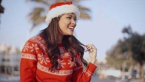 Beautiful Girl in Santa Claus Hat Smiling at Camera  She Wearing Red Woolen Sweater  Slow Motion Video