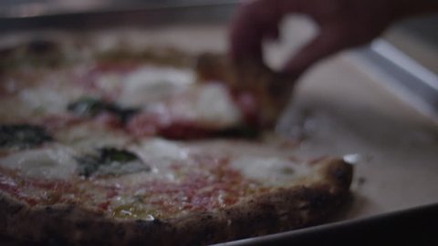 A hand grabs a slice of pizza with a shallow depth of field - 4k