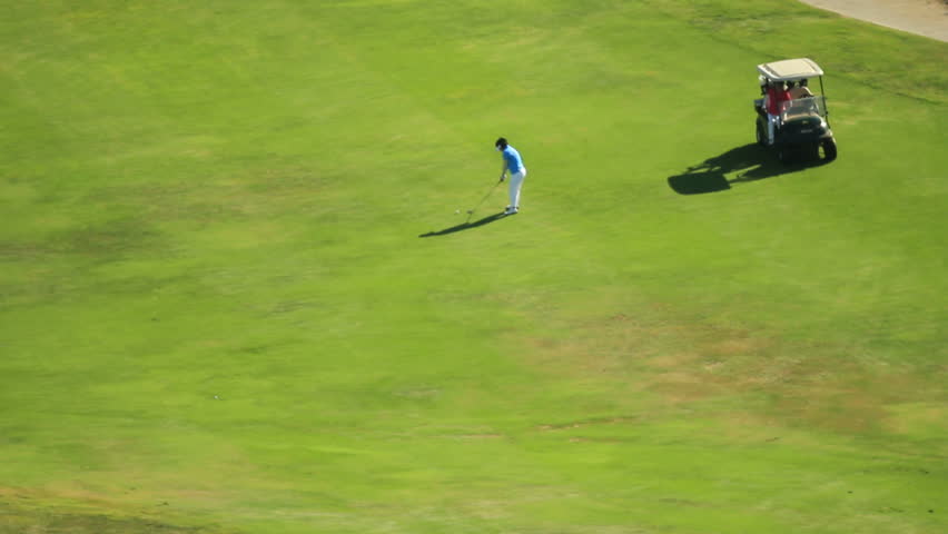 Wide shot of a golfer hitting a ball from the fairway
