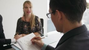 Clients meeting with financial consultant in corporate office. The couple holds their hands and talk with a self-absorbed advisor, who is doing a crossword puzzle. Medium shot, over the shoulders - Powered by Shutterstock - Get 15% off with code: PIKWIZARD15