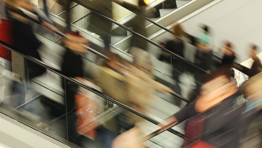 People on fast moving escalator in public building  