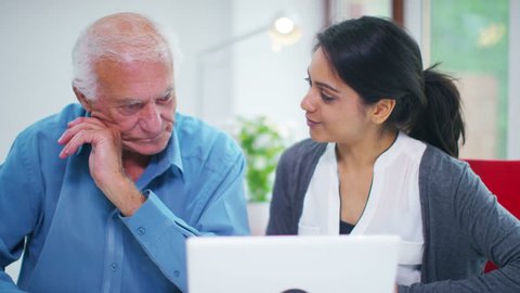 4K Cheerful young home support worker showing elderly gentleman how to use a computer. Shot on RED Epic